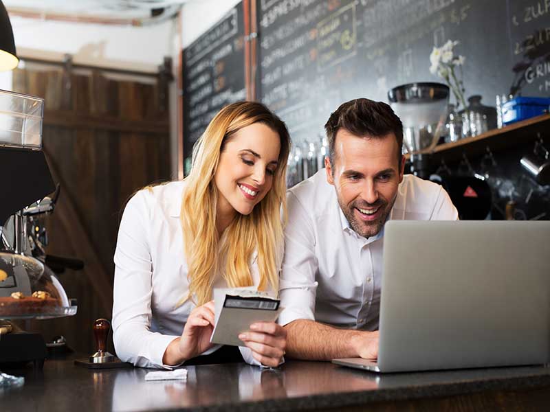 Two happy cafe managers working on laptop